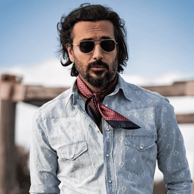 a men individual wearing a light blue floral-patterned denim shirt with a calm red neckerchief. a men individual wearing a light blue floral-patterned denim shirt with a calm red neckerchief.